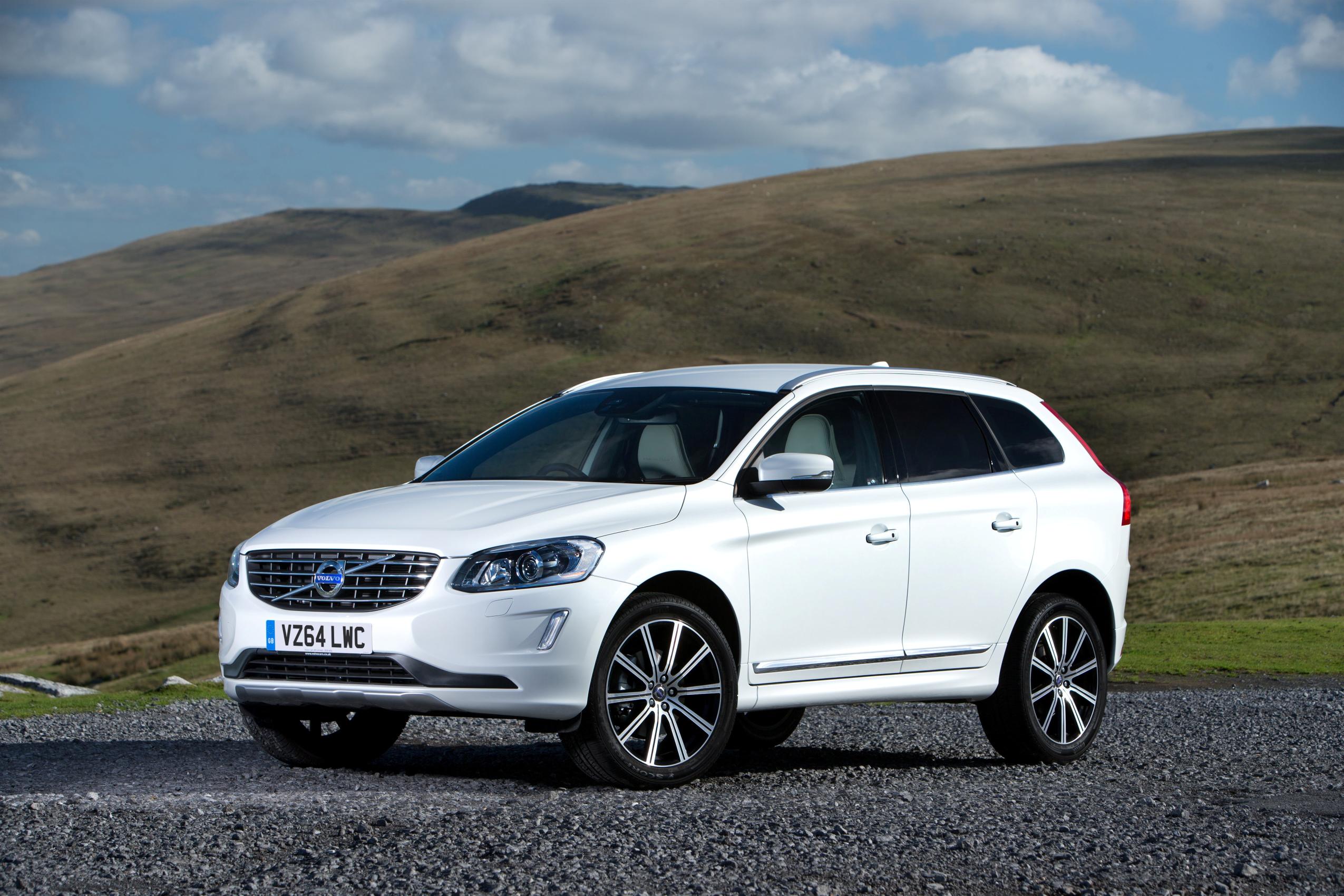 White Volvo XC60 parked facing left in front of hill range
